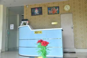 einen Schreibtisch mit einer Blume in einem Zimmer mit einer Uhr in der Unterkunft Hotel Buddha Vibrant in Deoghar