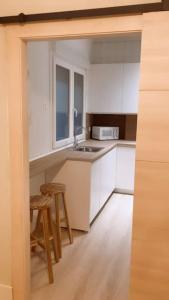 una cocina con armarios blancos, fregadero y taburete en BilboAppartment, en Bilbao