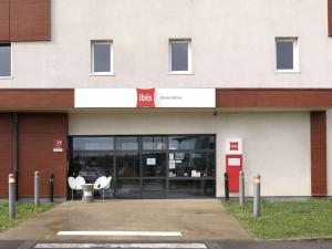 a building with two white chairs in front of it at ibis Douai Dechy in Dechy