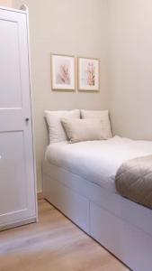 1 dormitorio blanco con 1 cama y 2 cuadros en la pared en BilboAppartment, en Bilbao