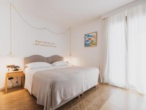 a white bedroom with a bed and a window at Tramas Hotel & Spa in Olbia