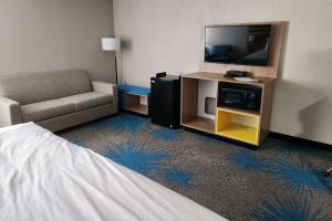 a hotel room with a bed and a tv and a couch at Days Inn by Wyndham Davenport in Davenport