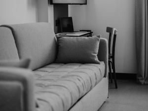 Greet Hotel Brest Aéroport في Guipavas: غرفة معيشة مع أريكة ومكتب مع الكمبيوتر المحمول