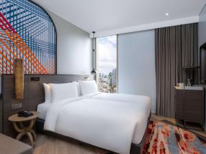 a bedroom with a large white bed and a large window at Mercure Bangkok Surawong in Bangkok