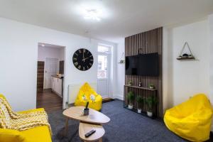 sala de estar con muebles amarillos y reloj en la pared en Open Mind Property - Luxury House & Free Parking, en Portsmouth