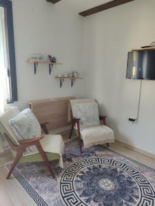 a living room with two chairs and a tv at Sobe RoomsBella in Ripač +11 photos