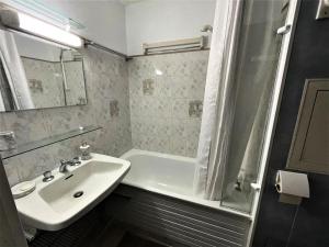 a white bathroom with a sink and a bath tub at Résidence Tougnette - Studio pour 3 Personnes 494 in Les Menuires