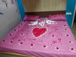 Una cama con un corazón hecho de flores rojas en MR staye, en Ooty