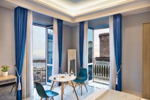 Cette chambre dispose d'une grande fenêtre et d'une table avec des chaises. dans l'établissement MAIN - Municipio, à Naples