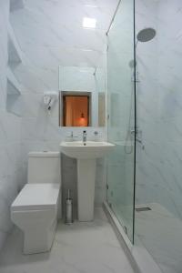 a white bathroom with a sink and a shower at Best Hotel Muqaddam in Bukhara