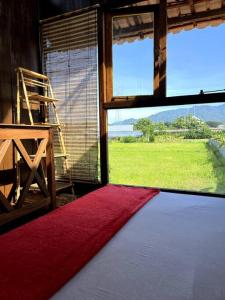 a room with a large window and a red rug at Di Kubu YR in Jembrana