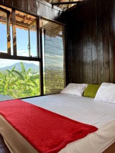 a bedroom with a large bed with a red blanket on it at Di Kubu YR in Jembrana