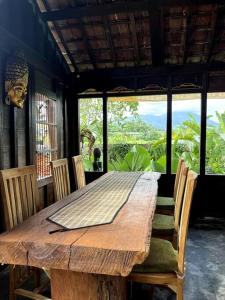 a wooden table with chairs and a large window at Di Kubu YR in Jembrana