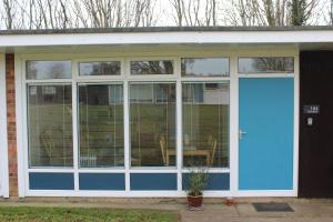 a screened in porch with a blue door at Stonesthrow 184 Broadside Chalet Park Stalham in Stalham
