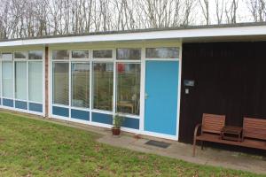 a building with a blue door and a bench at Stonesthrow 184 Broadside Chalet Park Stalham in Stalham