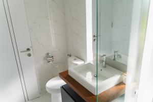a white bathroom with a sink and a toilet at Deluxe apartments Canggu area with gym coworking security parking and full services in Tumbak Bayuh