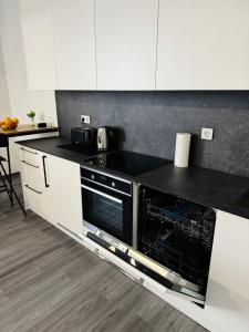 uma cozinha com armários brancos e um forno de fogão preto em Modern Studio Apartment in Riga em Riga