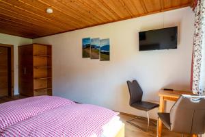 Schlafzimmer mit einem Bett, einem Schreibtisch und einem TV in der Unterkunft Mittereggalm in Mühlbach am Hochkönig