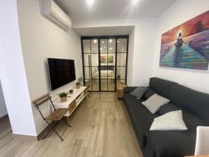 - un salon avec un canapé et une télévision dans l'établissement LA SUITE DES COULEURS - Apartamento en pleno centro de Córdoba - CÓRDOBA SUITES, à Cordoue