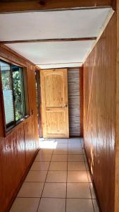 um corredor vazio com uma porta de madeira numa casa em Cabañas Mahatua em Hanga Roa