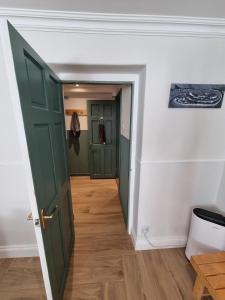a hallway with two green doors and wooden floors at South Road Room in Aberystwyth