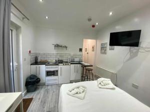 ブラックプールにあるReads Court Holiday Apartments - Blackpool Resort Collectionの白い家電製品付きのキッチン、白いベッドが備わる客室です。