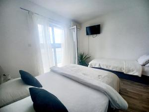 a bedroom with two beds and a television and a window at Apartmani Leženić Dada in Neum