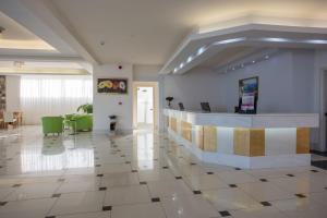 a lobby with a reception desk and green chairs at Kouros Palace in Mastichari