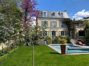 uma casa grande com uma piscina num quintal em Demeure de prestige au cœur de Rueil-Malmaison em Rueil-Malmaison