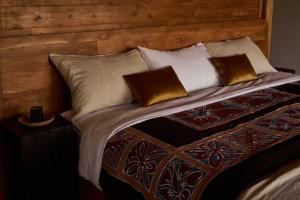a bed with a wooden head board and pillows at July Villas in Canggu