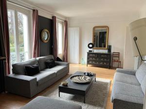 uma sala de estar com um sofá e uma mesa em Demeure de prestige au cœur de Rueil-Malmaison em Rueil-Malmaison
