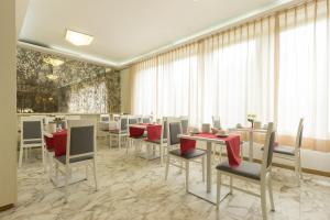 een eetkamer met tafels en stoelen met rode servetten bij Hotel Roma in Pisa