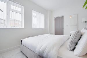 biała sypialnia z białym łóżkiem i oknami w obiekcie Apartment 1 Castle Lane w Bournemouth