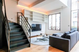 a living room with a staircase and a couch at Chic duplex loft in trendy Bastille in Paris