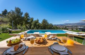 a wooden table with food and drinks on it next to a pool at Villa Sunset Split overviewing Split and Podstrana bay in Strožanac +42 photos