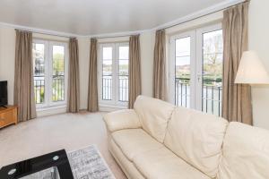 a living room with a white couch and windows at Large Tranquil Riverside Flat with Thames Views - Pass the Keys in Reading