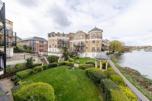 a building on a lawn next to a river at Large Tranquil Riverside Flat with Thames Views - Pass the Keys in Reading