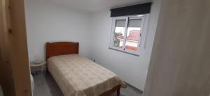 Ce petit lit se trouve dans une chambre blanche dotée d'une fenêtre. dans l'établissement Casa da Catraia - Remodelação recente nos quartos, à Póvoa de Midões