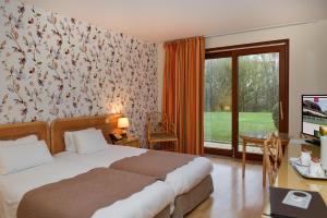 a bedroom with a bed and a desk and a window at Logis Le Relais De Pouilly in Pouilly-sur-Loire