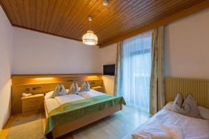 a hotel room with two beds and a window at Alpin Natur Hotel Brückele in Braies