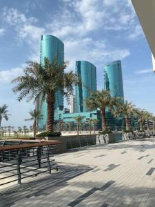 un parque con bancos, palmeras y edificios altos en Harbor Row, en Manama