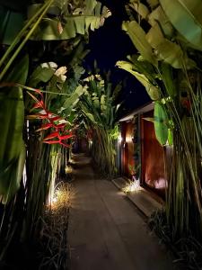 a hallway filled with lots of plants at night at The Clifton Canggu Seaside Villas in Canggu