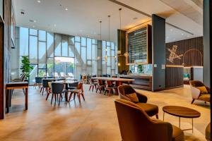 um restaurante com mesas, cadeiras e janelas em Courtyard by Marriott Santiago Airport em Santiago