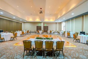 un salón de banquetes con mesas y sillas blancas en Courtyard by Marriott Santiago Airport en Santiago