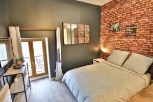 een slaapkamer met een bed en een bakstenen muur bij Big Apple - Studio paisible - parking gratuit - 2 personnes in Auxerre