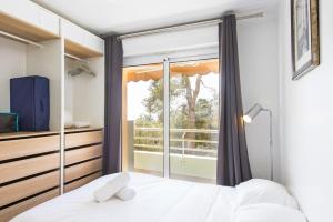 een slaapkamer met een bed en een raam bij Spacieux appartement - Parking privé & Piscine in Beausoleil
