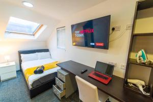 een slaapkamer met een bed en een bureau met een laptop bij Spacious Comfortable studio near the university in Birmingham