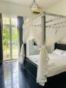 Roshe-Sky Guest House Colombo في Mahabage: غرفة نوم مع سرير مظلة مع ناموسيات بيضاء