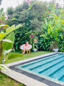 Roshe-Sky Guest House Colombo في Mahabage: شخص يجلس في حوض الاستحمام بجوار حمام السباحة