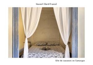 ヴォヴェールにあるGîte de vacances en Camargue ☆☆NNのベッドルーム1室(カーテン付きのベッド1台付)